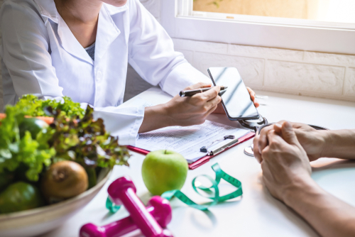 A naturopathic nutritionist shares information from their phone screen with a client
