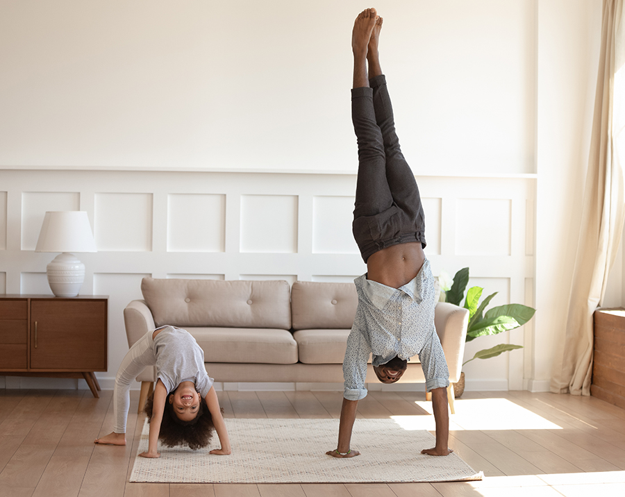 Active happy african american girl doing bridge exercise, strong father staying on hands. Smiling black family doing morning exercises together in living room at home. Daily healthy habit concept.