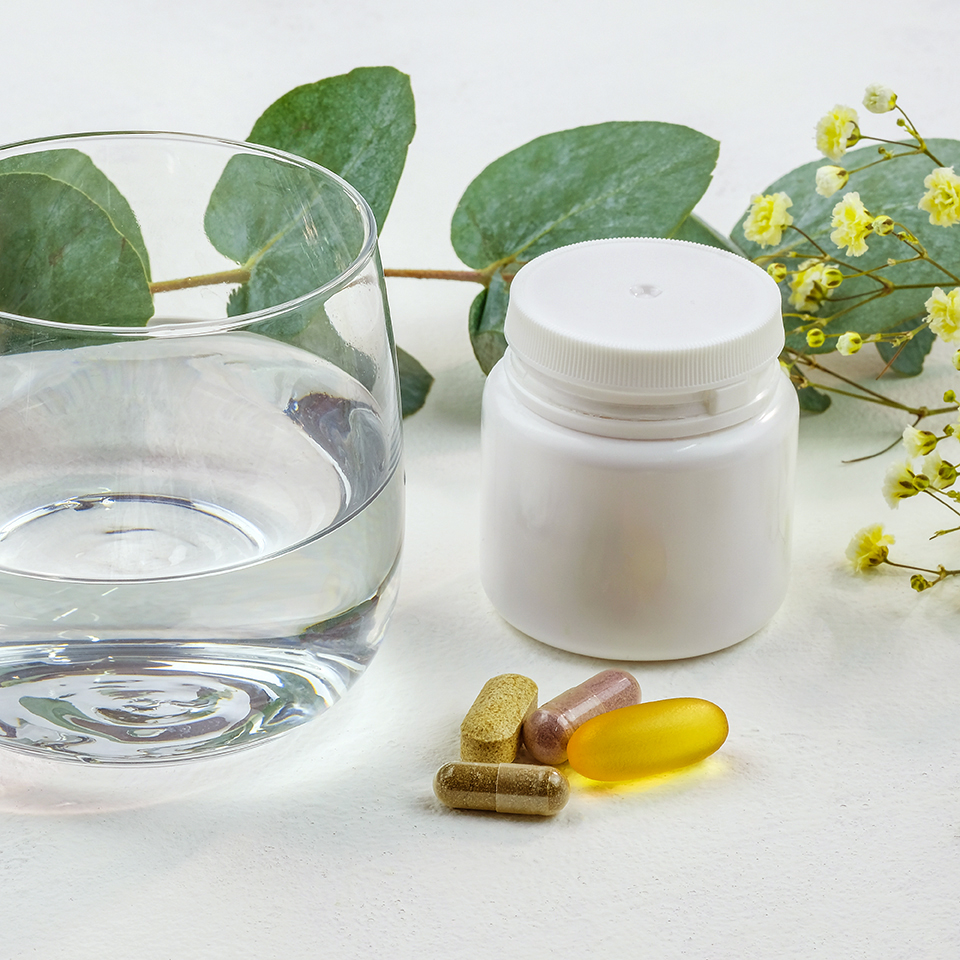 Glass of water and pills on a white background. Pills and a plastic water bottle. Taking dietary supplements. Food supplements to improve the functioning of the body. biologically active food