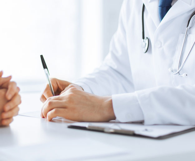 A closeup of a naturopathic doctor taking detailed notes while listening to a patient
