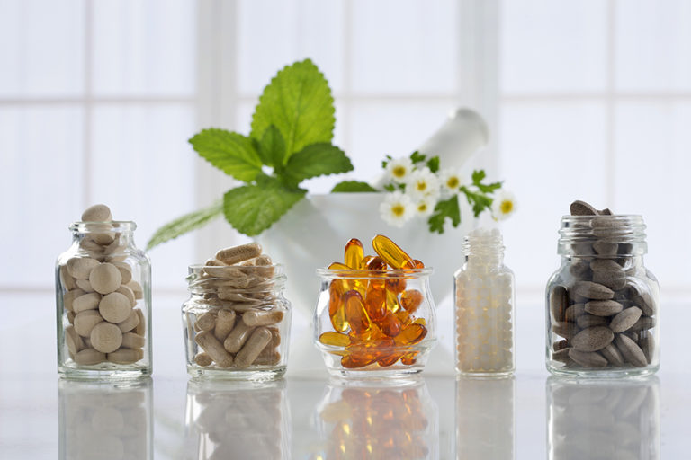 Herbal medicine pills and mortar over bright background